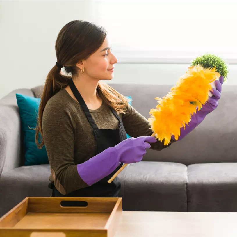 Mujer sacudiendo el polvo en casa