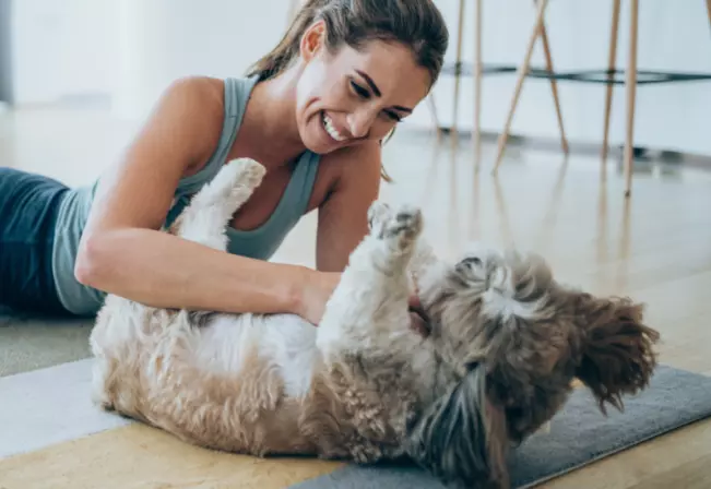 Mujer sentada en el piso junto a su perro.