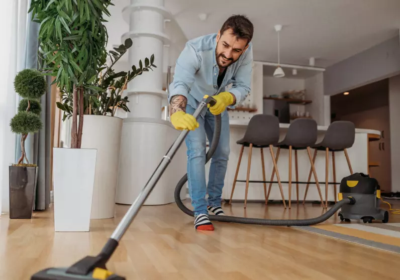 Hombre aspirando habitación en el día