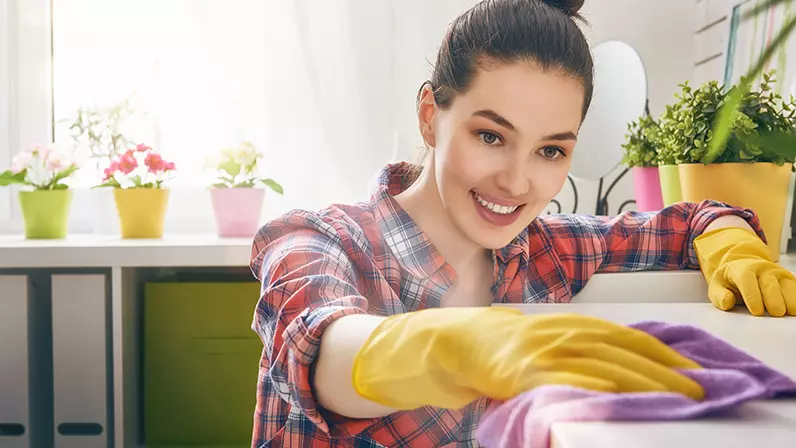 Mujer con guantes de plástico limpiando repisas